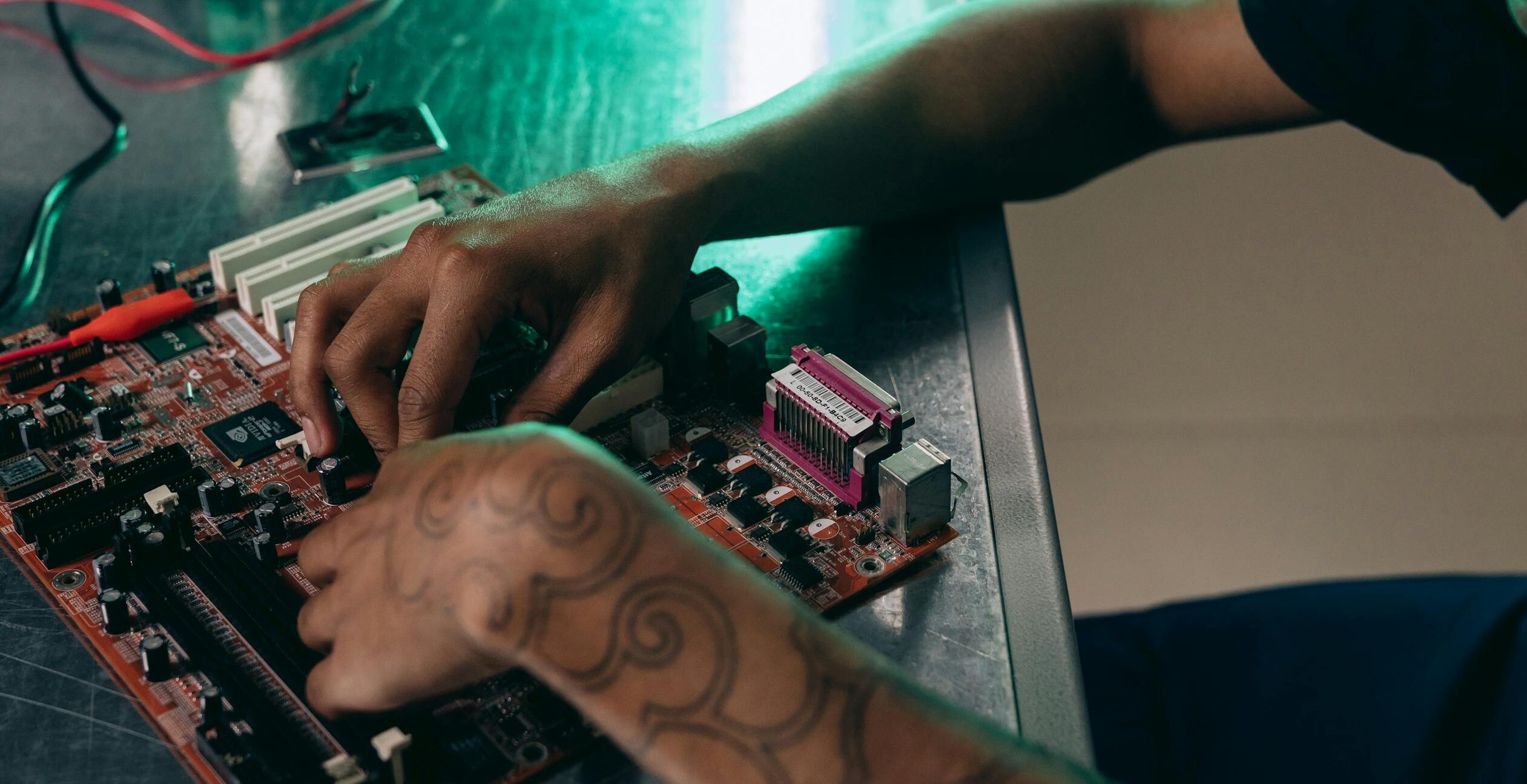 Close-up of person assembling a computer motherboard, showcasing a tattooed arm and tech innovation.