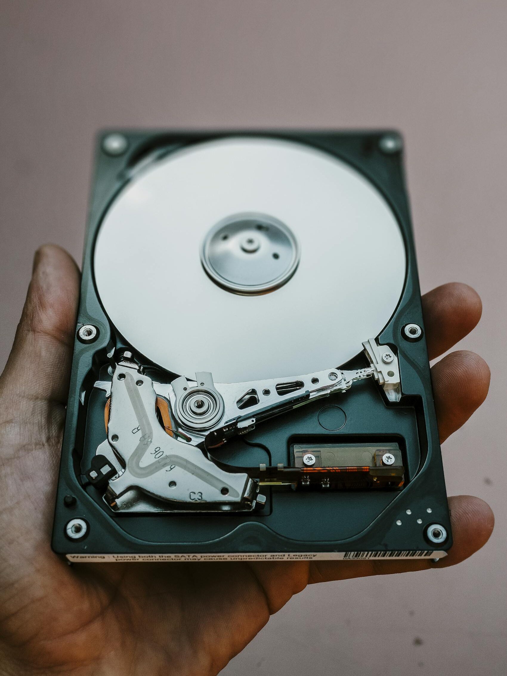 Close-up view of an open hard drive held in a hand, illustrating data storage technology.